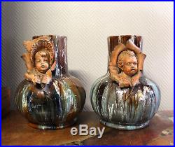 Superbe paire de vases vernissés bleu avec visages d'enfants dans des feuilles